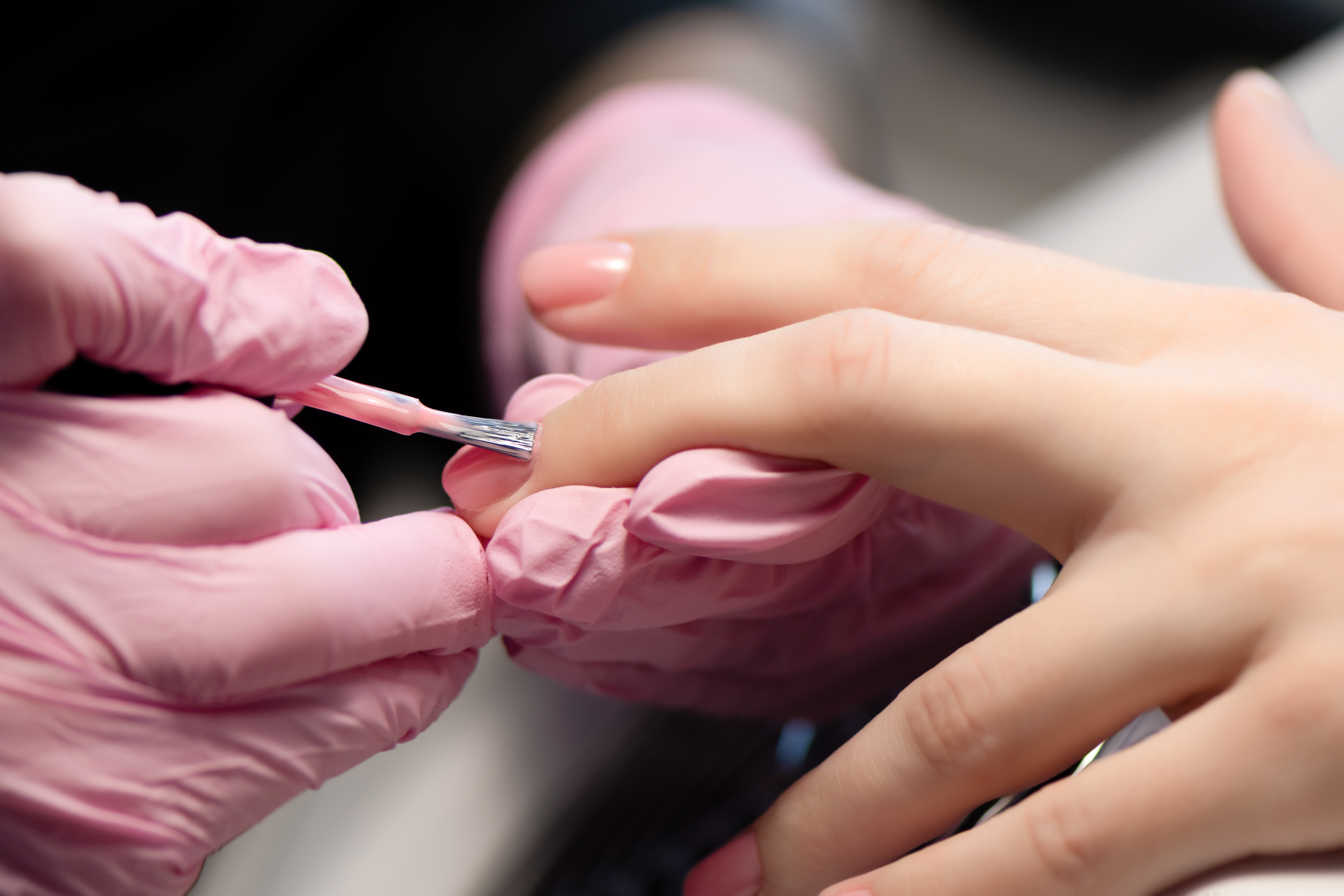 Manicurist doing gel nail design for client, close up